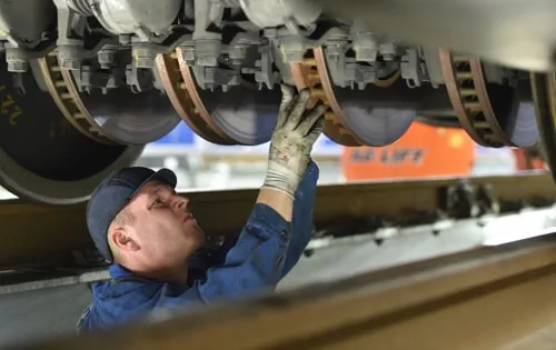 Mechaniker arbeitet unter einem Zug an dessen Technik.