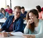Studierende sitzen in einem Hörsaal und arbeiten mit Unterlagen.