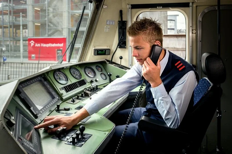 Lokführer im Führerstand telefoniert während der Zugfahrt.